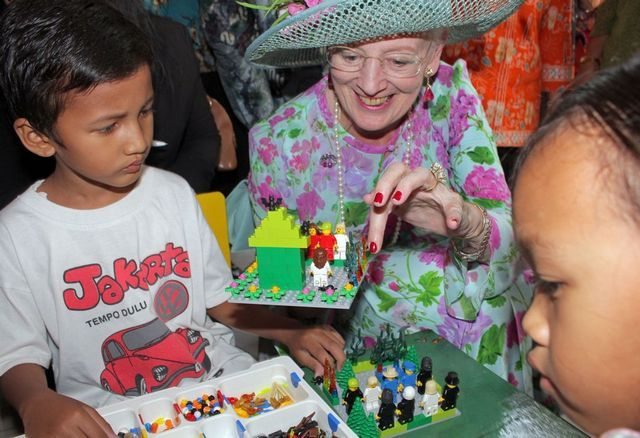 Danish Queen Margrethe II (C) interacts with children playing with Lego toys during a visit to inaugurate a children's park in Jakarta on October 22, 2015. Denmark's Queen Margrethe II is on a three-day state visit to Indonesia, accompanied by the Danish foreign minister and a trade delegation. AFP PHOTO / POOL / ADI WEDA